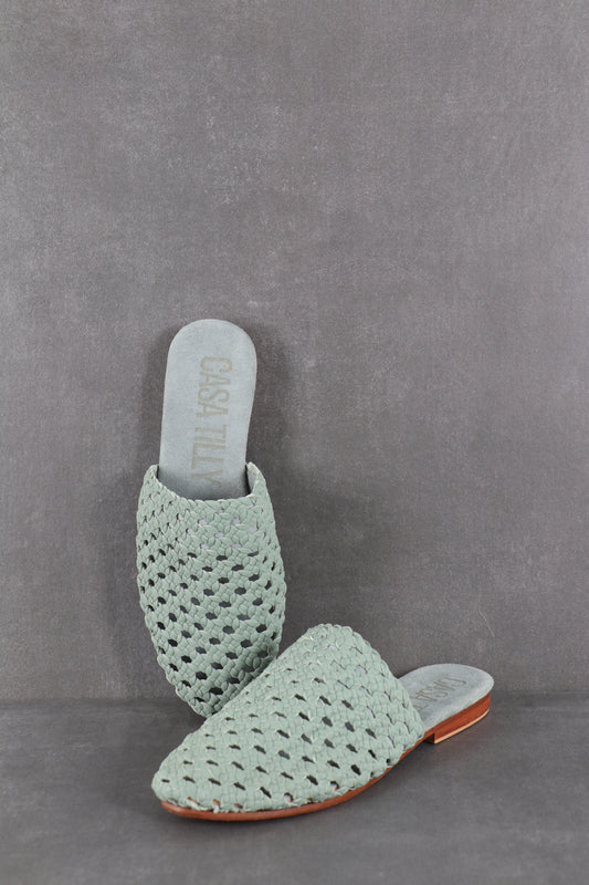 Mules plates tressées pistache en cuir pour femmes.